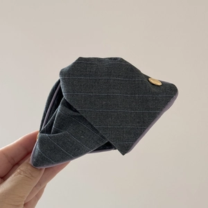 Détail de la texture en tissu gris à rayures et boucle en métal doré sur une pince à cheveux