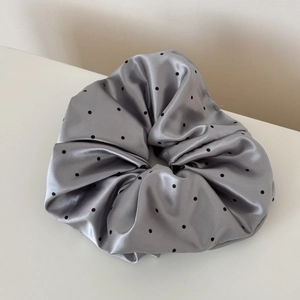 Detailed close-up of glossy silver satin scrunchie with black polka dots and full ruffles