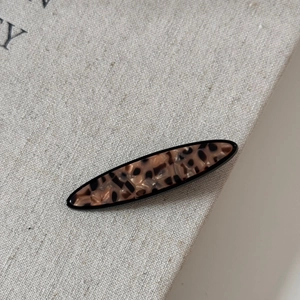 Detail of tortoise shell patterned hair clip on textured linen fabric background
