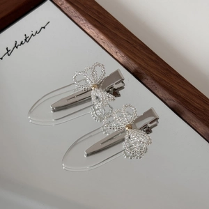 Close-up of handmade transparent beaded bow hair clips on a mirrored surface