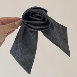 Gros plan d'une pince à cheveux rose en tissu rayé gris avec des rubans élégants