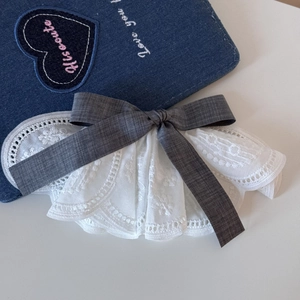 Detailed embroidery lace pattern with a textured grey linen bow hair clip accessory