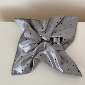 Macro detail of glossy silver satin scrunchie with classic black polka dots pattern