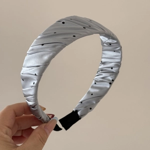 Detail of silver grey satin headband with black polka dots and pleated fabric texture