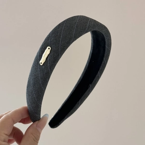 Détail d'une pince à cheveux en tissu rayé gris avec une plaque dorée fait main