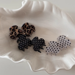 Close-up of six mini polka dot and leopard print hair claws on a shell-shaped tray