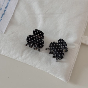 Close-up of mini black and white polka dot hair claws on a stylish beige background