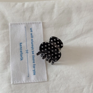 Detailed view of a mini black hair claw with white polka dots on elegant fabric