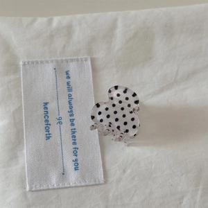 Close-up of mini polka dot hair claw clip in creamy white with black dots decoration