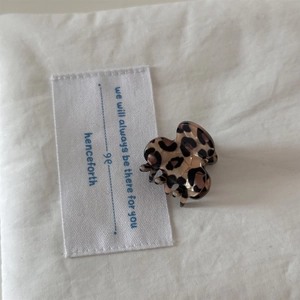 Close-up of a mini leopard print hair claw clip on soft beige fabric background