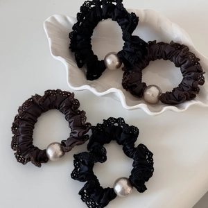 Detailed view of satin scrunchies featuring delicate lace trim and large faux pearl accents