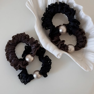 Close-up of silk lace hair scrunchies with pearls in black and brown on shell tray