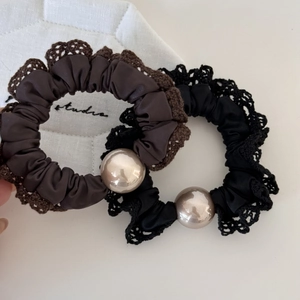 Detailed shot of two satin hair scrunchies with lace trim and elegant large pearls