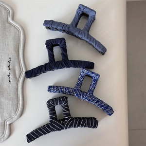 Detailed close-up of four denim fabric wrapped shark hair clips in assorted blue patterns