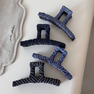 Detail view of four vintage denim and striped fabric wrapped claw clips for hair styling