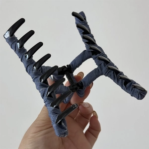 Detail of large hair claw clip featuring blue denim fabric wrap and black glossy finish