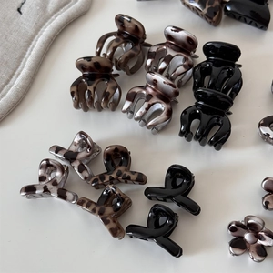 Detail view of mini leopard print and black acrylic hair claws in flower and ring shapes