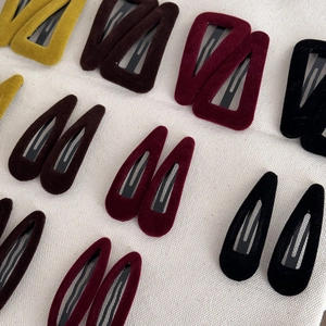 Détail macro de barrettes en velours aux couleurs vintage sur un tissu en lin
