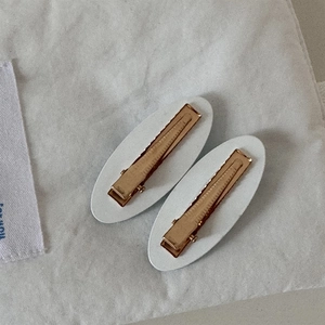 Vue détaillée de l'arrière des pinces dorées avec base en similicuir texturé crème