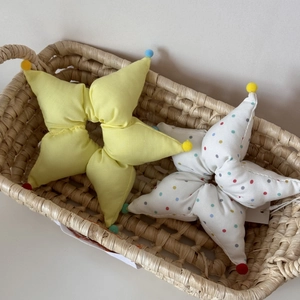Détail de chouchous en tissu en forme d'étoile avec mini pompons colorés dans un panier