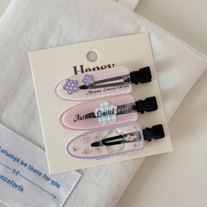 Détail d'un lot de barrettes en acrylique à fleurs et étoiles sur carte en tons roses