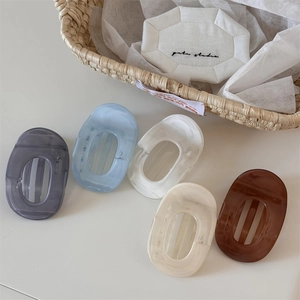 Flat oval hair claw clips in five macaron colors on a white minimalist surface