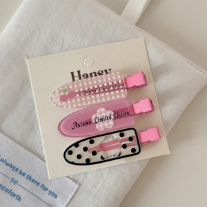 Gros plan détaillé de trois barrettes à cheveux en acrylique rose floral sur carte blanche