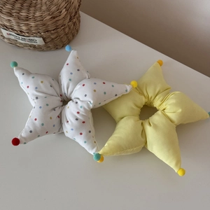 Détail de chouchous en tissu en forme d'étoile avec pois et pompons doux colorés