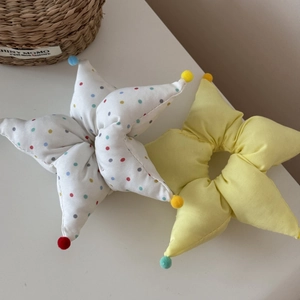 Détail de chouchous en tissu en forme d'étoile avec pompons colorés et motifs à pois
