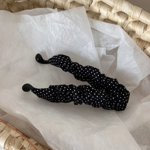 Detaillierte Nahaufnahme der Retro-Polka-Dot-Stofftextur auf einer schwarzen Haarspange
