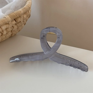 Vista dettagliata di una grande pinza per capelli grigia traslucida con molla in metallo dorato