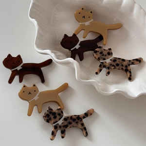Chic leopard and acetate cat-shaped hair clips in amber and yellow on a white plate