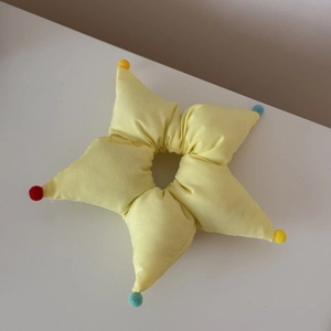 Détail d'un chouchou en forme d'étoile jaune avec de petites balles en peluche