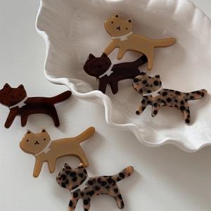 Close-up of tortoise shell and acetate cat hair clips on white ceramic tray