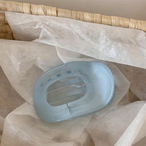 Detail view of light blue matte hair claw clip with oval hollow design on white paper