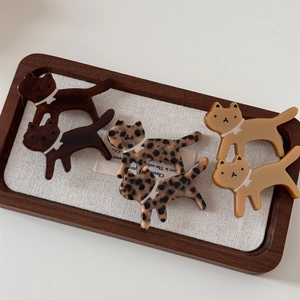 Detailed view of six cat-shaped acetate hair clips in leopard and solid brown patterns