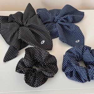 Detailed view of four polka dot hair scrunchies with bows in black and navy colors