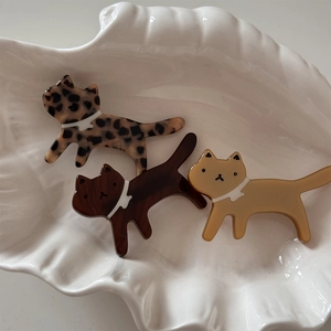 Detailed macro view of leopard print acetate cat hair clips in a white shell dish