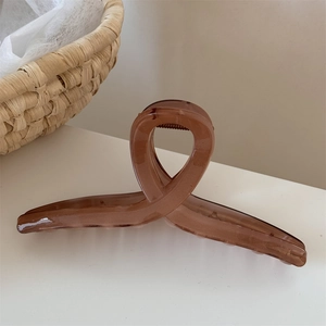 Dettaglio della molletta per capelli ambra traslucida con design a incrocio elegante