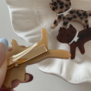 Macro detail of leopard print acetate cat hair clips showing the golden metal duckbill clips