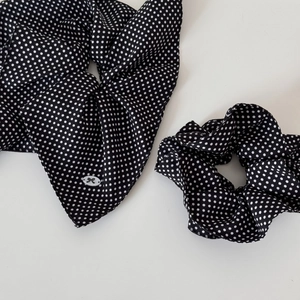 Detailed view of polka dot hair scrunchies with white bow logo detail on fabric