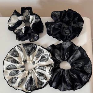 Close-up of four pleated scrunchies with black and white abstract leaf patterns