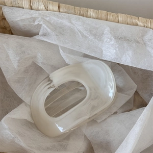 Macro shot of cream white marble resin hair claw with smooth glossy finish and oval cutout