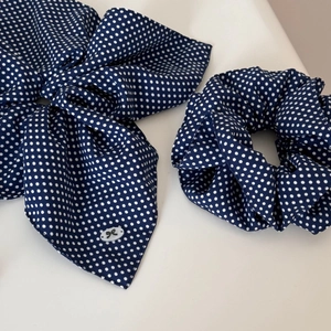 Close-up of navy blue polka dot hair scrunchie and bow headband set with fine fabric texture
