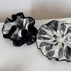 Detail of two pleated scrunchies in black and white shell pattern on white background