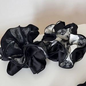 Close-up of pleated scrunchies with black and white abstract patterns on a white surface