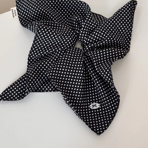 Detail of black polka dot hair scrunchie with handmade label and bow accent