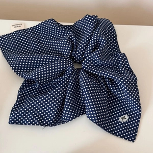 Detailed view of navy polka dot scrunchie with handmade label and bow logo detail