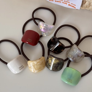 Close-up of 8-piece hair tie set with multicolored resin charms and gold handmade text