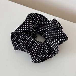 Close-up of black and white polka dot hair scrunchie with soft fabric texture